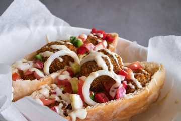 Authentic fresh falafels balls inside of two halves of pita bread sandwich with chopped salad and drizzle of tahini sauce on top, close-up of chickpea falafel in a gluten-free pita 