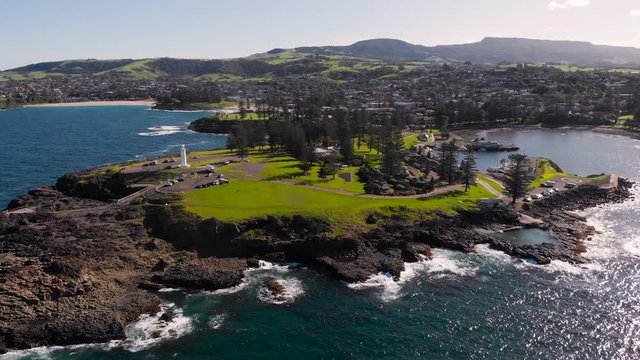 Kiama, a resort town in Australia. An aerial view of the picturesque rocky headland. A white lighthouse stands on the ocean.