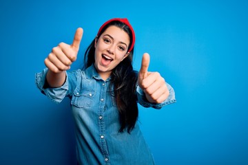 Young brunette woman wearing casual denim shirt over blue isolated background approving doing...