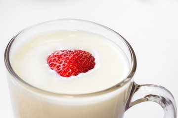 red fresh ripe sweet strawberries floating in cow's milk poured in a clear glass glass on a white background Breakfast place for text