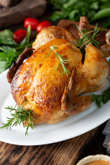 Whole Roasted Chicken on white plate with rosemary, sauces and vegetables