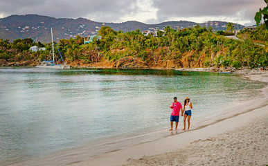 A couple walking hand in hand along beach shoreline