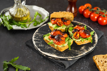 Vegan sandwiched with mashed avocado, roasted tomatoes and arugula