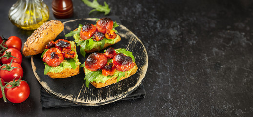 Delicious vegan sandwiches with mashed avocado, roasted tomatoes and arugula