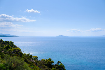 Amazing view from green hill to the  turquoise water and blue sky with island and white clouds in the background
