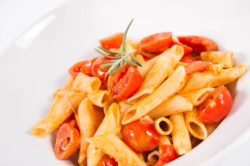 Penne with tomatoes, garlic and mozzarella decorated with rosemary twig, on a white background