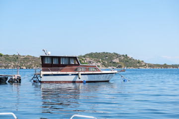 Old brown living boat in blue water with green hill in the background