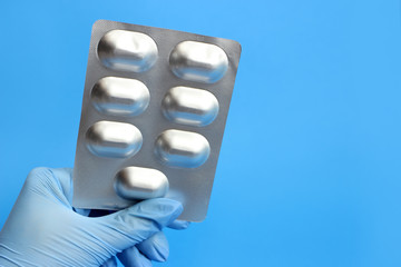 A blister of pills in the hand of a nurse, a doctor in a glove
