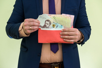 businessman receives money as a bribe in envelope. a man gives a whole bunch of hryvnia Ukrainian money in  envelope