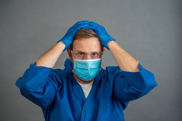 Male doctor feeling exhausted after long shift treating coronavirus infected patients at hospital