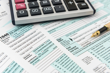 Fototapeta na wymiar Tax form, pen and calculator at office desk