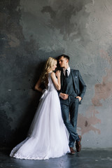 Cute wedding couple in the interior of a classic studio decorated. They kiss and hug each other.