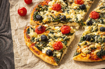 Homemade pizza with spinach, tomatoes and olives.