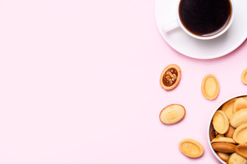 Homemade Russian nuts with condensed milk on a light pink background, wafer napkin. Cut nuts with condensed milk. Bitten goodies for coffee.