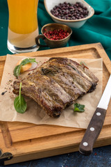 Juicy Grilled Pork Ribs Meat on Wooden Board with glass of beer on green background