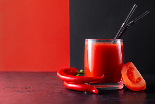 Glass Of Tomato Juice With Tubes, Fresh Tomato Slice And Chili Pepper On A Black And Red, Vegetable Juice