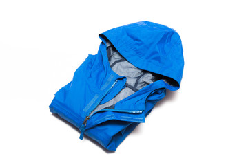 Folded blue zipper windbreaker jacket, rain proof and waterproof hiking Gore-Tex jacket hoodie. Track jacket sport nylon full zip isolated on white. Folded clothes. Outer layer garment for travel.