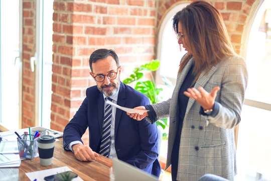 Two middle age business workers working together. Woman bullying man at the office