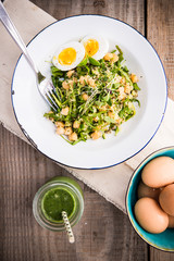 Boiled Eggs salad with burgul, rise and quinoa on a wooden table with green juice, from above. Healthy quinoa salad with tomatoes, avocados, eggs, herbs. Leaves, lettuce.
