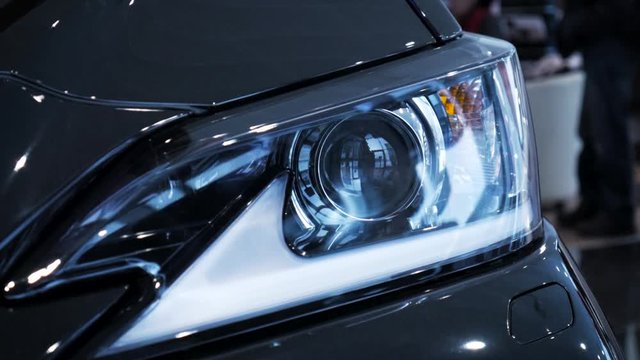 Closeup video left car headlight side span of the camera. Stock. Modern techonology auto details with led and xenon elements inside.