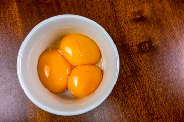 Egg yolks separated in porcelain ramekin on wooden table