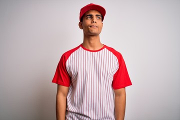 Young handsome african american sportsman wearing striped baseball t-shirt and cap smiling looking to the side and staring away thinking.