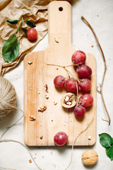 Food photo: branch of red grapes and walnuts on wooden board, on light background, top view. Sloppy still life.
