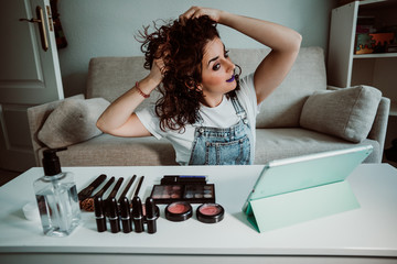 .Young woman making a video tutorial on how to style her curly hair to include it in her blog....