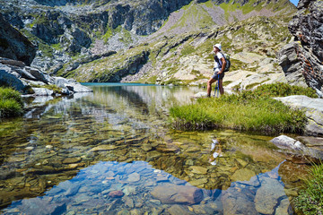 backpacker resting near a mountain lake in a beautiful summer's day