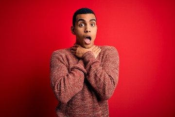 Young handsome african american man wearing casual sweater standing over red background shouting and suffocate because painful strangle. Health problem. Asphyxiate and suicide concept.