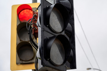 Red traffic light hanging on the background of a turned off traffic light. traffic regulation in...