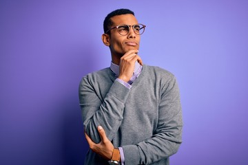 Handsome african american businessman wearing glasses and tie over purple background with hand on...