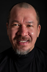 Studio Portrait of a Handsome Mixed Race Man with a Beard Smiling, on Black background