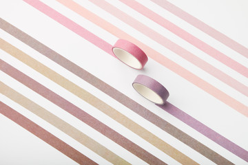 Two adhesive tape rolls and parallel strips on white background