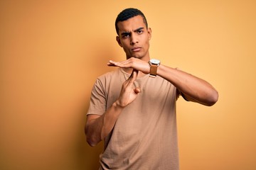 Young handsome african american man wearing casual t-shirt standing over yellow background Doing...