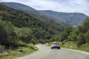 Fototapeta premium White car slowing down before turning on mountain road. Concept of dangerous roads, low visibility on serpantine roads.