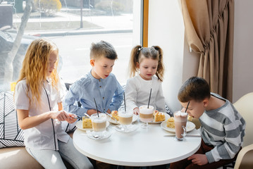 A large friendly company of children celebrate the holiday in a cafe with a delicious dessert. The day of the birth