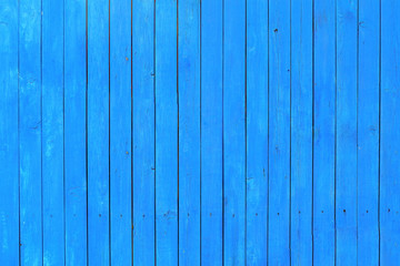 Texture of a wooden fence painted with blue paint. Closeup.
