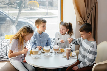 A large friendly company of children celebrate the holiday in a cafe with a delicious dessert. The day of the birth