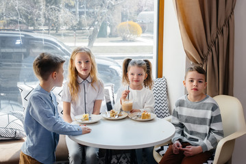A large friendly company of children celebrate the holiday in a cafe with a delicious dessert. The day of the birth