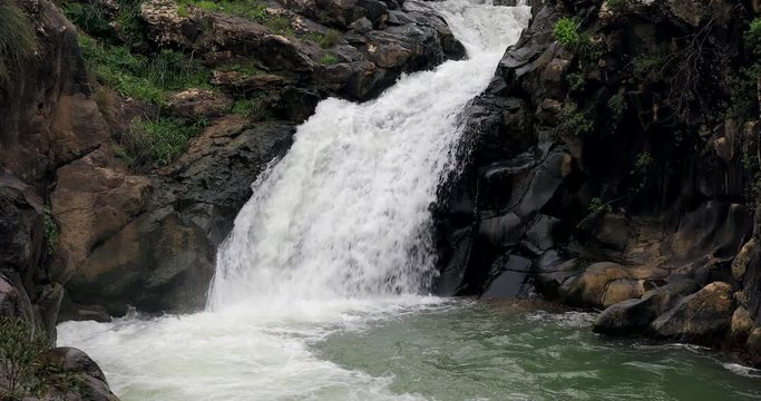 High waterfall and greenery all around.