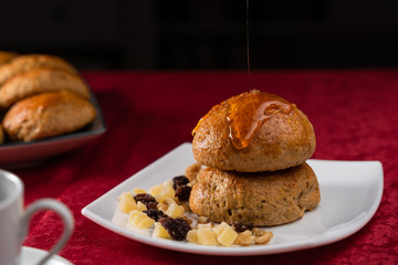 Dessert, snack or breakfast of two  delicious british buns drizzled in honey or maple syrup. On a...