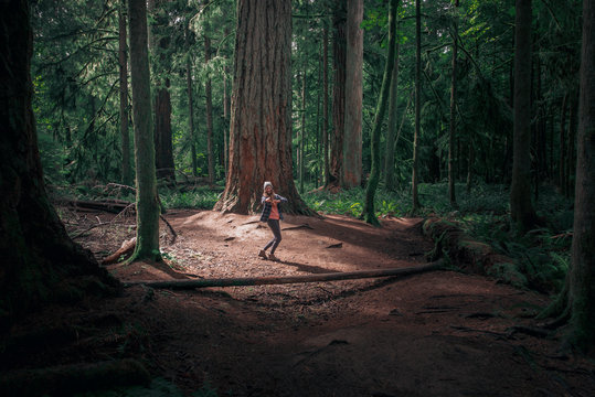 Woman looking back smiling and showing with finger in forest MacMillan