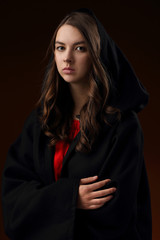 Portrait of a pretty girl in a black Cape with a hood
