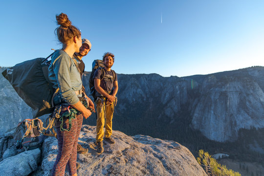 Three hikers at the top of El Capitan in Yosemite Valley at sunset