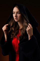 Portrait of a pretty girl in a black Cape with a hood