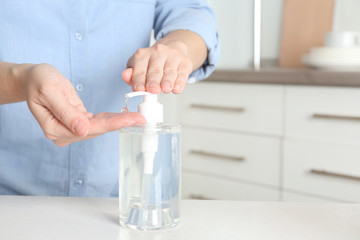 Woman applying antiseptic gel on hand indoors, closeup. Space for text