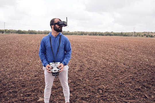 young man flies drone with glasses in the field