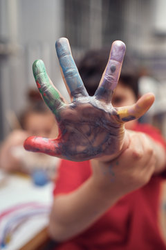 boy shows his water-colored hand while playing with his sister