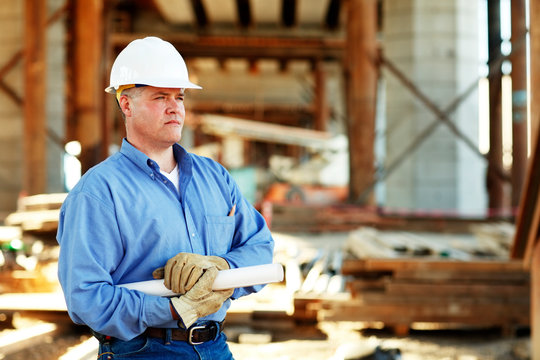 Male construction foreman holding plans looking off camera